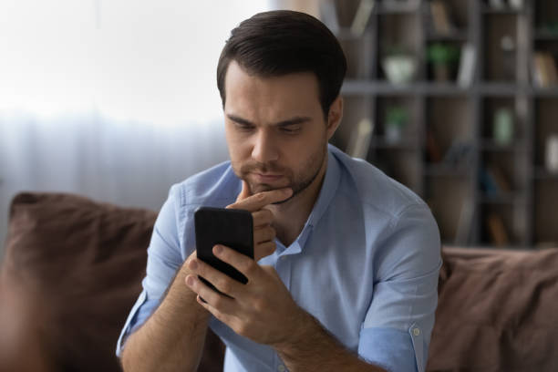 istock Thoughtful millennial man rubbing chin reading important phone message 1442364839