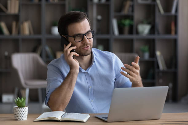 istock Millennial businessman sit by pc advising client by phone 1442364931