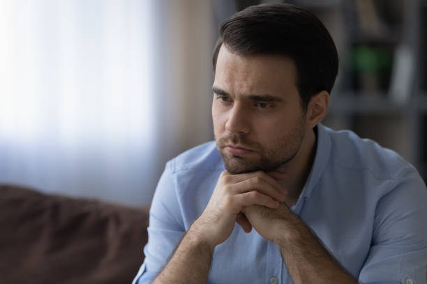 istock Young man put chin on hands lost in bad thoughts 1442364932