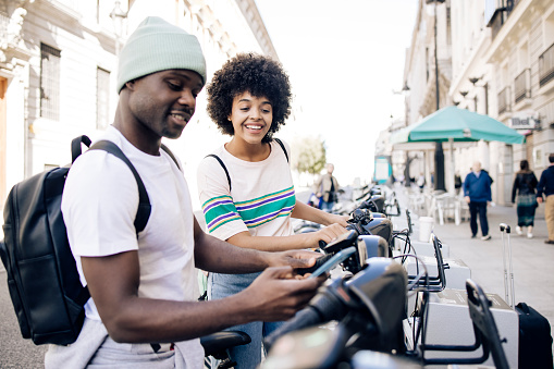 Young African American couple renting e-bikes to explore Madrid.