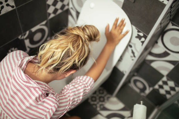An unrecognizable woman vomits in the bathroom stock photo