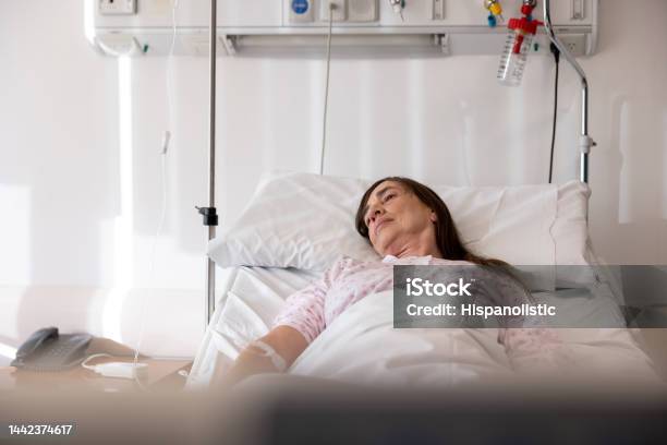 Sick Woman Lying In Bed At The Hospital Stock Photo - Download Image Now - Hospice, IV Drip, 60-64 Years