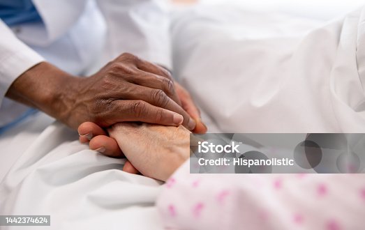 istock Close-up on a doctor holding the hand of a sick woman in bed at the hospital 1442374624