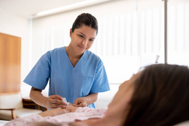 Nurse putting an IV line on a hospitalized patient Latin American nurse putting an IV line on a hospitalized patient â healthcare and medicine concepts catheter stock pictures, royalty-free photos & images