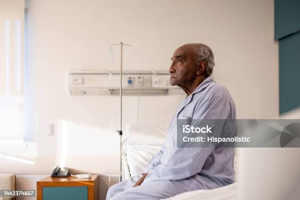 Sick Man Sitting On The Bed In His Room At The Hospital Stock Photo - Download Image Now