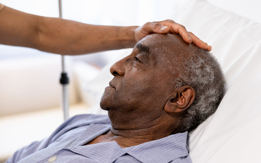 Close-up on a sick senior adult being visited at the hospital by his son - healthcare and medicine