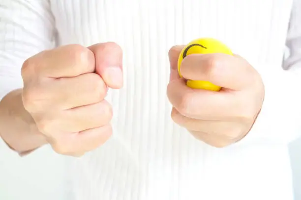 Hands of man with a gentle personality He exhibits stressful behavior from work, and he squeezes the yellow ball expressing emotion, anger, displeasure. Medical concepts and emotional regulation