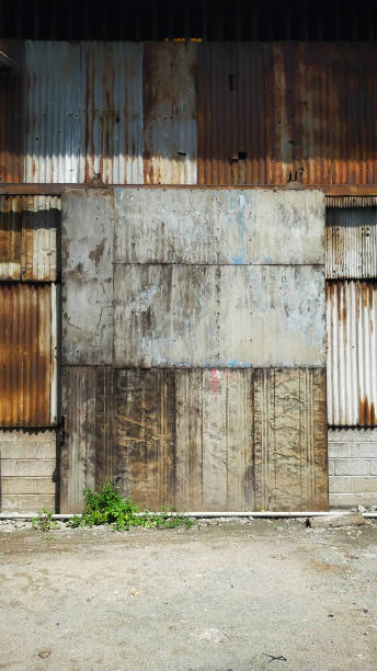 istock Old building covered with rusty corrugated tin walls and rolling door. 1442383755
