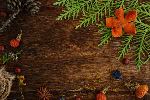 Christmas or New Year composition on dark wooden background. Decorative frame made in christmas tree branches, Spruce branches, pine cones, herbs, nuts, juniper berries, rose hips
