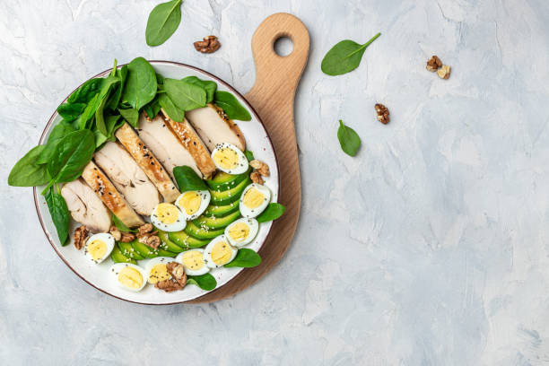Ketogenic diet food, chicken fillet, quail eggs, avocado, spinach, walnut. healthy meal concept on a gray background, top view stock photo