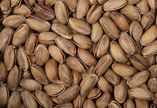 Gaziantep pistachios (Antep fıstığı) in shell as a background. The kernels are often eaten whole, either fresh or roasted and salted, and are also used in ice cream and confections such as baklava.