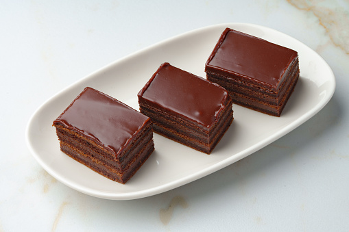 Three piece of chocolate brownie cake on white plate close up