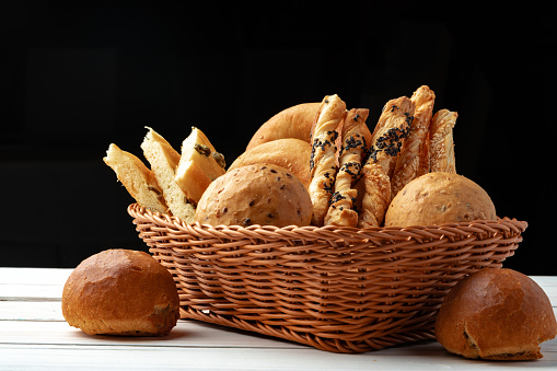 Bakery products in straw bread basket on wooden table close up