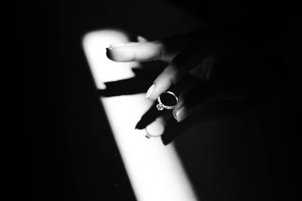 A bride hand showing off her engagement ring whit a small light isolated on a dark surface