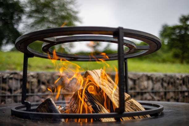 metallfeuerstelle mit dem holz, das in den heißen flammen auf einem natürlichen, verschwommenen hintergrund draußen brennt - fire pit fire camping burning stock-fotos und bilder