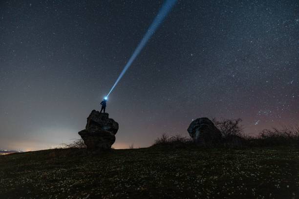 istock Man with a head flashlight on a background of a beautiful night starry sky 1442405512