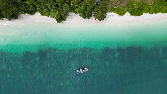 An aerial shot of a boat floating on the water surface near the Langkawi Island, Malaysia