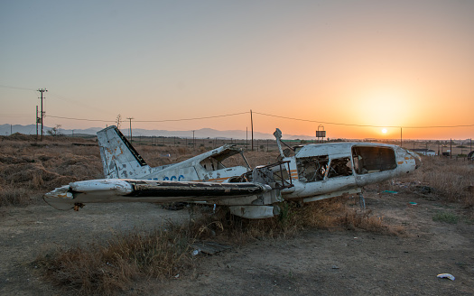 A beautiful image of an old broken airplane in an isolated area with a mesmerizing sunset background