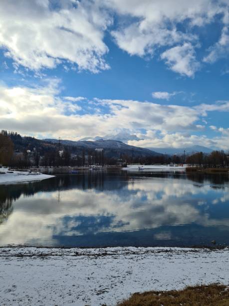 istock Winter scene with lake, snowy shore and trees under blue cloudy sky 1442407188