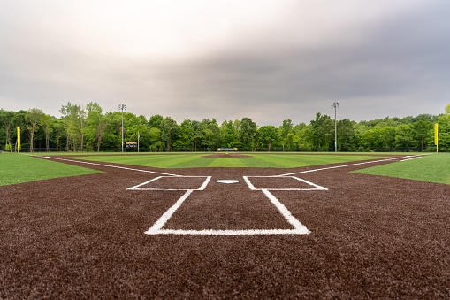 A scenic view of a baseball field with artificial grass in cloudy sky background