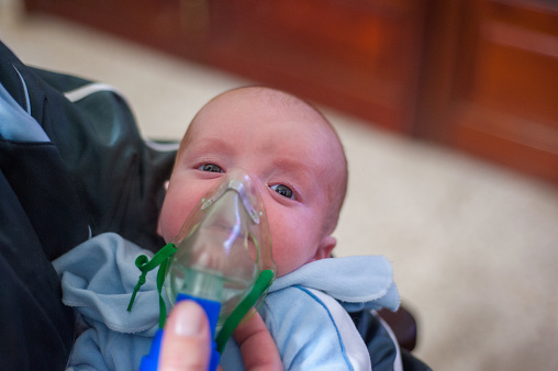 Closeup of a cute newborn its mother's arms, breathing with the help of an oxygen mask