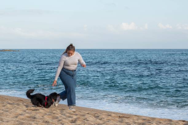 istock Woman and dog playing on the beach 1442412903