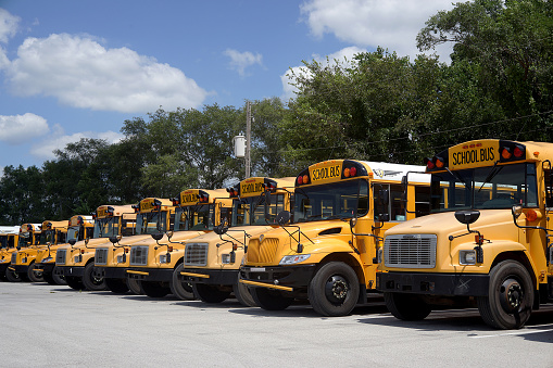 Kansas City, United States – October 11, 2021: A shot of yellow School buses parked in parallel in a yard parking for service repair during daytime