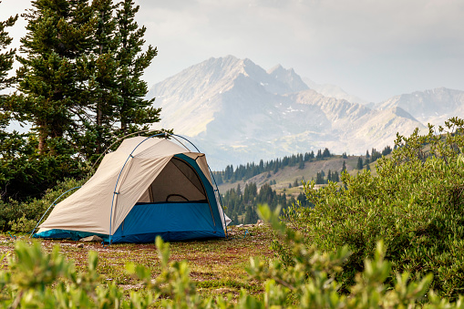 A tent against the background of forest and mountains.