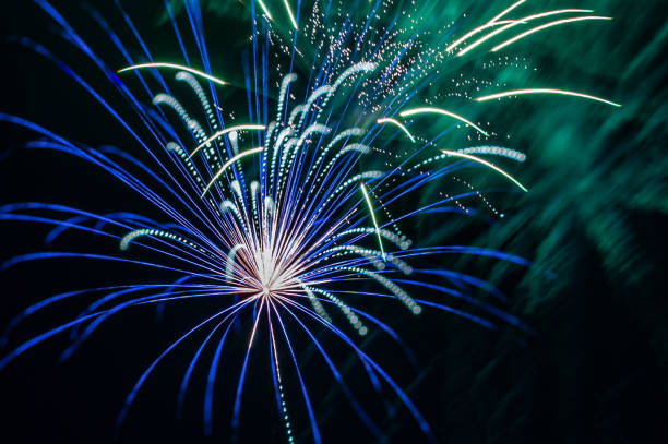 A firework explosion in green and blue colors in the night sky