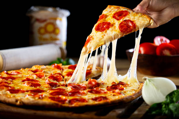 persona recibiendo un pedazo de pizza de pepperoni con queso - pizza fotografías e imágenes de stock
