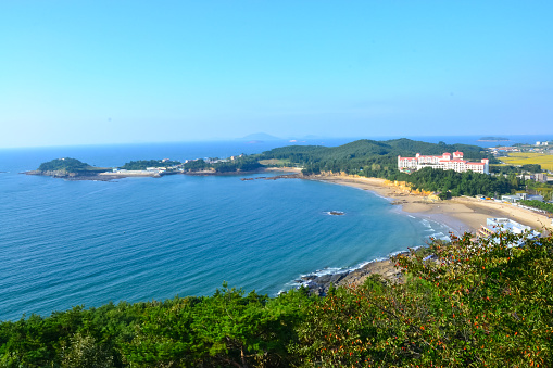 A beautiful shot of the beach and a white building on the hill in Byeonsan-Bando National Park, South Korea.