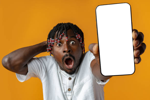 istock Excited young african man holding smartphone with white blank screen in hand on yellow studio background 1442419624