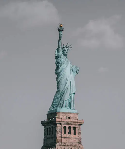 A vertical shot of the Statue of Liberty standing at Liberty Island at Hudson River in New York,
