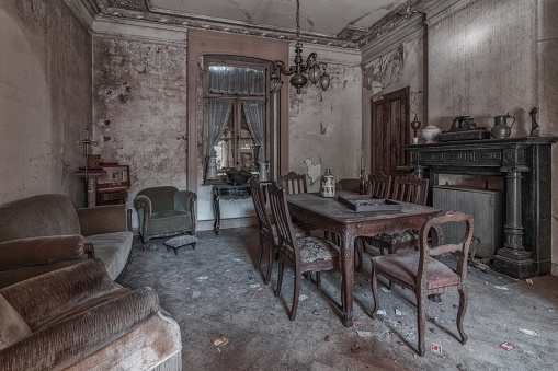 Dining room of an abandoned house with a table and chairs, beautiful dilapidation