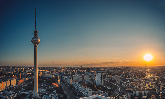 A scenic shot of the tv tower in berlin rising above all buildings with a sunset background