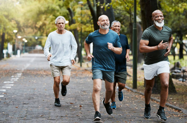 Senior, man group and running on street together for elderly fitness and urban wellness with happiness. Happy retirement, smile and runner club in workout, diversity and teamwork in park for health senior, grupo de hombres y corriendo juntos en la calle para el fitness de los ancianos y el bienestar urbano con felicidad. feliz jubilación, sonrisa y club de corredores en entrenamiento, diversidad y trabajo en equipo en parque para la salud