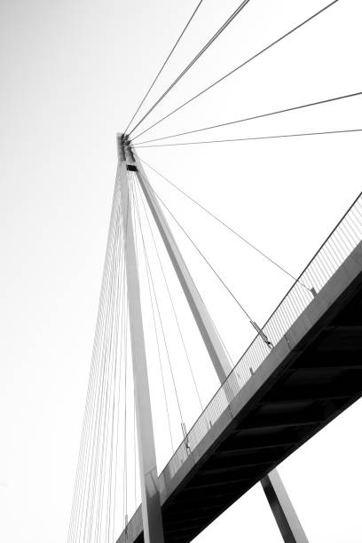 A vertical low angle closeup view of a road welded metal cable-stayed bridge on a white background