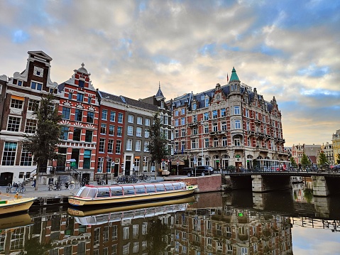 Amsterdam, Netherlands – October 03, 2022: A beautiful reflection on water at early morning sunrise in Amsterdam with old buildings
