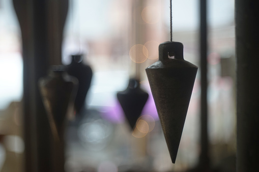 A plumb bob in the blurred background; leveling string weight tools
