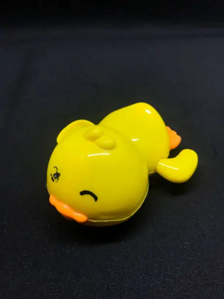 a yellow duck toy with a black background