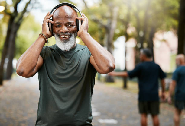 music, fitness and running with a senior black man in a park for cardio exercise or an endurance workout. portrait, happy and health with a mature male runner outdoor for training or wellness - senior adult human face male action imagens e fotografias de stock