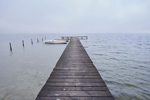 Wooden jetty or pier on lake in a foggy mood.