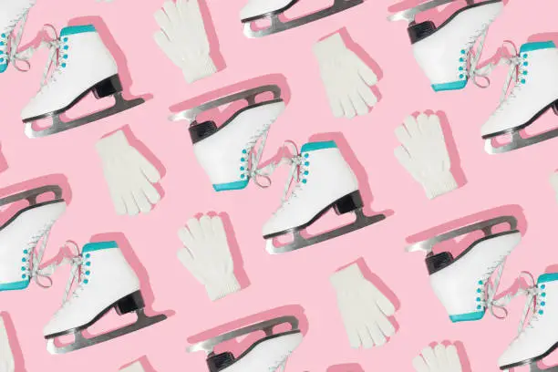 Winter creative pattern made with retro skates and white mittens on pastel pink background. Retro aesthetic 80s or 90s fashion background. Minimal winter sports concept.