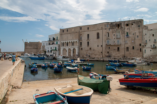 Monopoli, Italy. 06 28 2019. Panoramic of the old port with its boats anchored or docked at the pier and surrounded by old buildings.