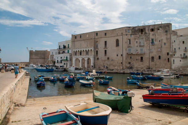 Fishing boats anchored in the port of Monopoli. Monopoli, Italy. 06 28 2019. Panoramic of the old port with its boats anchored or docked at the pier and surrounded by old buildings. monopoli puglia stock pictures, royalty-free photos & images