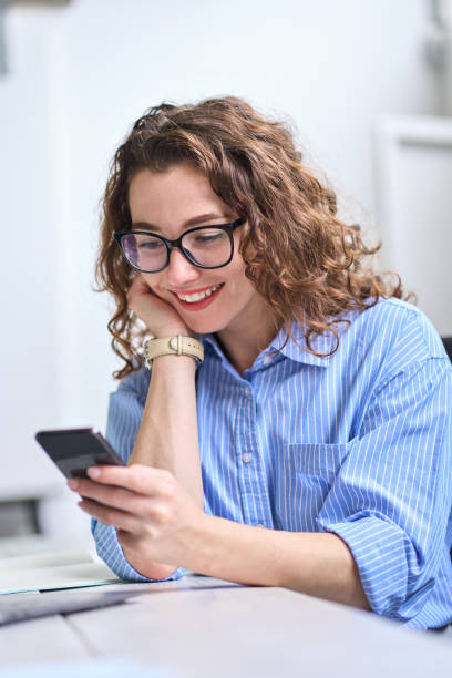 istock Happy young business woman using cell phone working in office, vertical. 1442441921