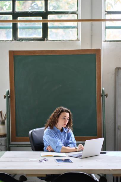 istock Female online teacher or coach having remote class on laptop in classroom. 1442441937
