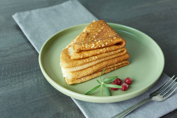 istock Appetizing pancakes with lingonberries on a green plate, close-up. 1442443544