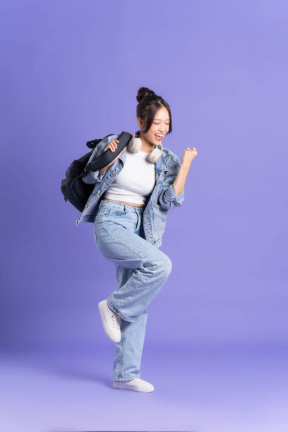 retrato de una hermosa colegiala asiática con una mochila sobre un fondo púrpura - filipino ethnicity audio fotografías e imágenes de stock