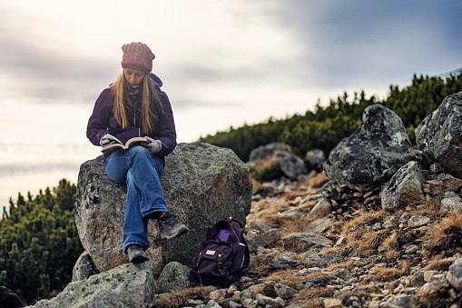 Teenage girl is hiking in the Tatras - Slovakia. She is having a break on a difficult trail high in the mountains and reading a book.

Canon R5